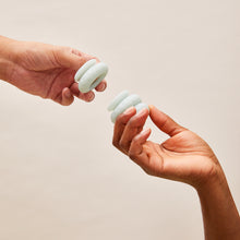 Charger l'image dans la galerie, Deux mains tenant les anneaux en polymère Ohnut de couleur vert jade sur fond couleur crème