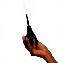 Charger l&#39;image dans la galerie, Main pressant la douche anale noire Squirt de Wednesday co. sur fond blanc
